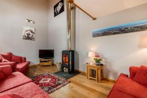 a living room with a red couch and a wood stove at Kidwelly Farm Cottage in Kidwelly +23 photos