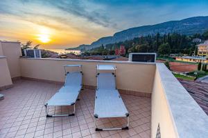dwie ławki siedzące na balkonie z widokiem na zachód słońca w obiekcie La Cà del Picia w mieście Garda
