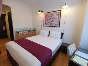 una habitación de hotel con una cama y una foto en la pared en The Royale Chulan Hyde Park Hotel, en Londres