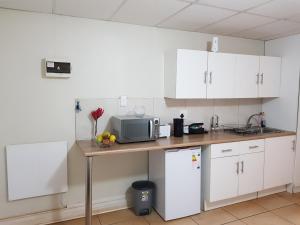 cocina con armarios blancos y encimera con microondas en CHEETAH MANOR #2 en Bloemfontein