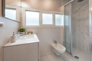 ein weißes Bad mit einem Waschbecken und einer Dusche in der Unterkunft BnButler Friuli, 24 - Porta Romana Apartment in Mailand