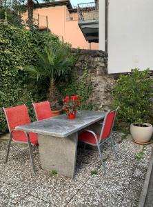 ベリンツォーナにあるCasa Nataliya, via tampori 8 6503 Bellinzonaの赤い花のテーブルと椅子4脚