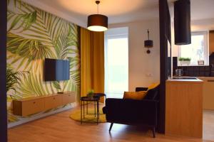 W&K Apartments - Gold Suite في كوشالين: غرفة معيشة مع أريكة وتلفزيون على الحائط