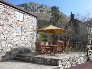 a table and chairs with an umbrella in front of a building at Panorama Cottages in Llangollen