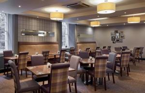 Leonardo Edinburgh City في إدنبرة: مطعم فيه طاولات وكراسي في الغرفة