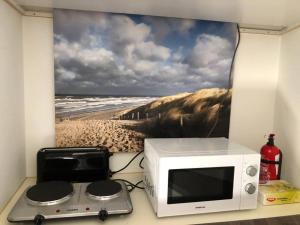 un forno a microonde su un bancone con una foto di una spiaggia di La Casita Alta Free Parking a Noordwijk aan Zee