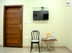 a chair and a table with a television on a wall at HOTEL BABYLON REGENCY, Opp Krishna Janmabhoomi Temple in Mathura