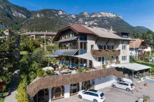 a building with cars parked in a parking lot with mountains in the background at Residence La Terrazza in Caldaro