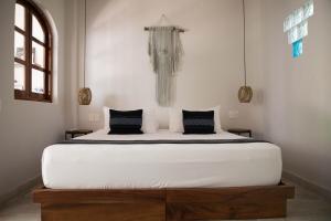 a bedroom with a large white bed with black pillows at PAL.MAR Hotel Tropical in San Francisco
