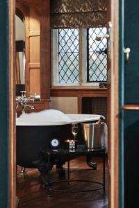 a bath tub sitting in a bathroom with a window at Great Fosters - Near Windsor in Egham