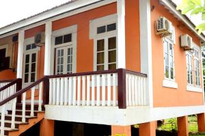 an orange and white house with a balcony at Ana Chaves Residence in São Tomé
