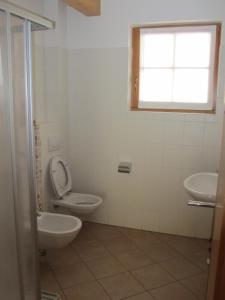 a bathroom with a toilet and two sinks and a window at La Pezina in Livigno