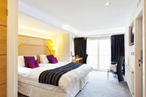 a hotel room with a large bed with purple pillows at Queens Mansions: Elizabeth Suite in Blackpool