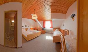 a bedroom with two beds and a large wooden ceiling at Hotel Twengerhof in Tweng