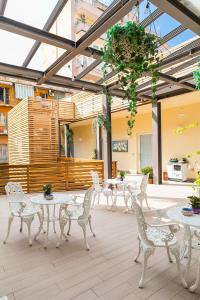 un patio con sillas y mesas blancas y techo de cristal en Borghetto Guest House, en Roma