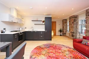een keuken en een woonkamer met een rode bank bij JOIVY Elegant 2BR Home at The Heart of the Royal Mile in Edinburgh