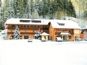 a large building with cars parked in the snow at Hotel Twengerhof in Tweng