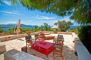 a patio with chairs and a table and a umbrella at Captain Mike's Villa in Syvota