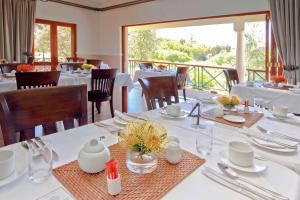 Montagu Vines Guesthouse في مونتاغو: غرفة طعام مع طاولات وكراسي بيضاء