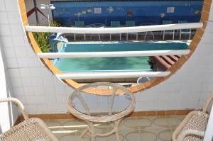 a chair and a swimming pool in a room at Hotel Gaivota in Itacuruçá