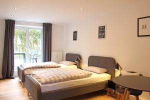 duas camas num quarto com uma mesa e uma janela em Moderne 1-Zimmer Wohnung mit Terasse, Küche, Bad mit Dusche, TV & WIFI em Burgwedel