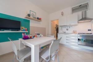 een witte keuken met een witte tafel en stoelen bij Babyaccommodation Family Comfort in Pietra Ligure