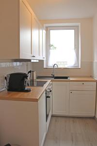 a kitchen with white cabinets and a sink and a window at Moderne 1-Zimmer Wohnung mit Terasse, Küche, Bad mit Dusche, TV & WIFI in Burgwedel