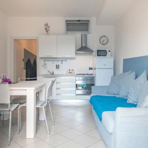a white kitchen with a white table and a white couch at Babyaccommodation Family Comfort in Pietra Ligure