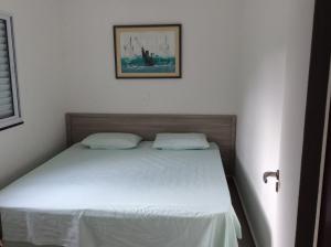 una camera da letto con un letto con lenzuola bianche e una foto di Village com 4 APTOS PÉ NA AREIA E PISCINA a São Sebastião Altre 21 foto