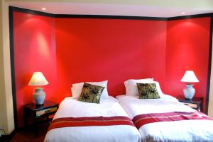 two beds in a room with a red wall at Sunset Apartment Phuket in Patong Beach