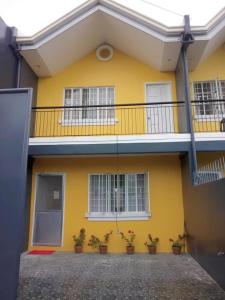 a yellow house with a balcony and potted plants at Diodeth's Apartments in Butuan