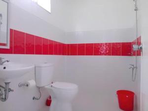 a bathroom with a toilet and a sink and red tiles at Diodeth's Apartments in Butuan +7 photos