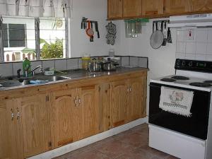 una cucina con mobili in legno e un forno a piano cottura di Candles in the Wind a Bon Accord Village