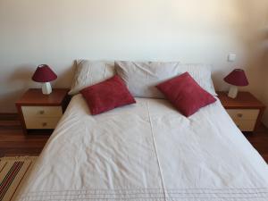 a white bed with two red pillows on it at Apartment at White Lavina Hotel in Bansko