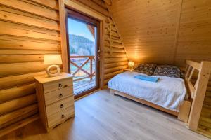 ein Schlafzimmer mit einem Bett und einem Fenster in einem Blockhaus in der Unterkunft DOMKI SWOJSKIE CHATKI in Szczytna