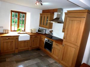 a kitchen with wooden cabinets and a stove top oven at Dolmurgoch Snowdonia Cottage in Dolwyddelan