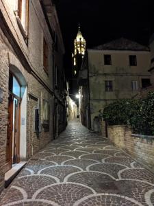 an empty street at night with a clock tower in the background at Hotel Du Parc in Atri