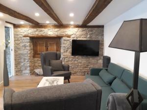a living room with a couch and a tv on a stone wall at Plaza Catedral Jaca in Jaca
