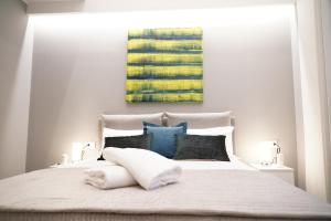 - une chambre avec un grand lit blanc et des oreillers bleus dans l'établissement Three Houses Toledo, à Naples