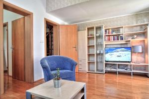 a living room with a blue chair and a television at Apartments Jojo in Bovec