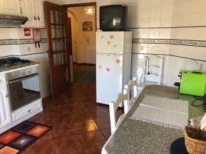 a kitchen with a refrigerator and a table with a tv on top at Casa do Rodrigo in Mondim de Basto