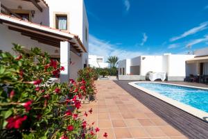 a villa with a swimming pool and red flowers at Apartamentos Mar y Sal in La Savina