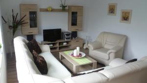 uma sala de estar com um sofá branco e duas cadeiras em Ferienhaus Jendral em Blankenburg