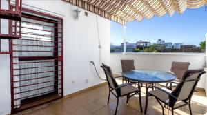 ein Esszimmer mit einem Tisch, Stühlen und einem Fenster in der Unterkunft Ático Conil Playa con piscina, garaje, 2 terrazas-BBQ, Aire Ac y WIFI -SOLO FAMILIAS Y PAREJAS- in Conil de la Frontera