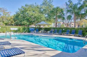 a swimming pool with blue lounge chairs and an umbrella at Newly Remodeled Hilton Head Villa in Hilton Head Island