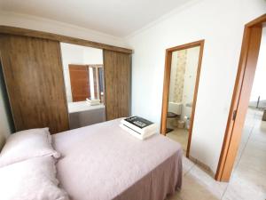 Un dormitorio con una cama con un libro. en Apartamento Praia das Toninhas, 3 min do Mar, en Ubatuba