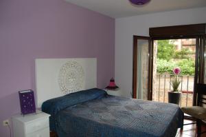 a bedroom with a bed with a blue comforter and a window at Casa Cascabelera in Ayllón