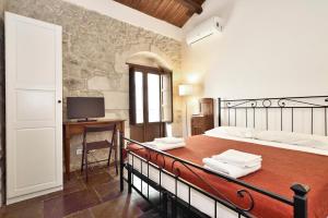 a bedroom with a bed and a desk and a television at Suite Piccolo Giavante in Ragusa