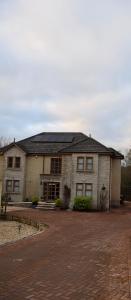een groot bakstenen huis met zonnepanelen erop bij Kelpies Serviced Apartments Kavanagh- 5 Bedrooms in Bathgate
