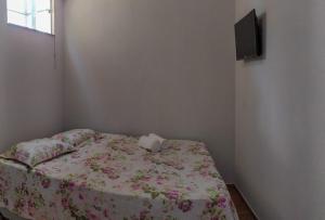 een slaapkamer met een bed met bloemrijke lakens en een televisie bij KITNET'S DA DENI in Alto Paraíso de Goiás